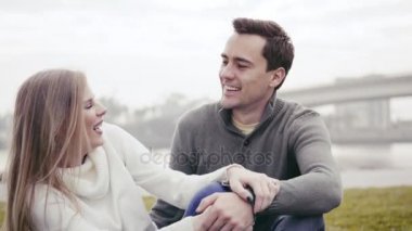 Çimenlerin üzerinde oturan ve bir parkta sarılma aşık Çift