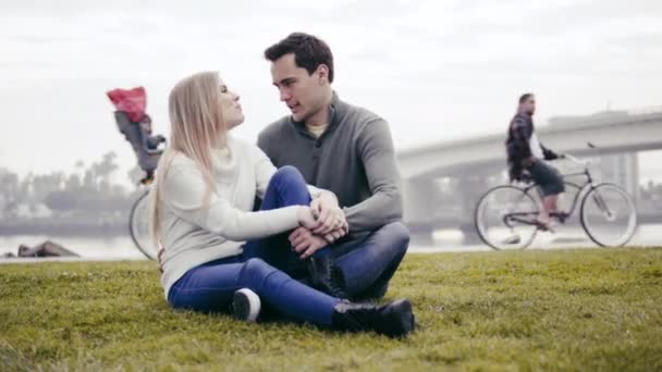 Pareja enamorada sentada en la hierba y abrazándose en un parque — Vídeo de stock