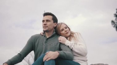 Çimenlerin üzerinde oturan ve bir parkta sarılma aşık Çift