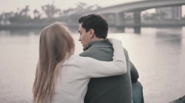 Çimenlerin üzerinde oturan ve bir parkta sarılma aşık Çift