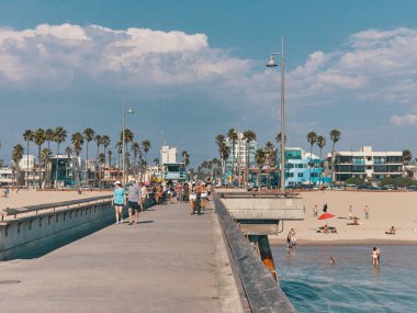 Pier üzerine yürüyüş insanlar ve kumsalda güneşlenmek. Venice Beach iskelesinden görünümü