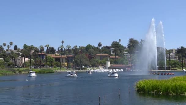 Los Angeles, Kalifornie, USA - 28. srpna 2019: Echo Park Lake. Trysky fontány dopadly vysoko. Lidé jezdí na lodích. Teplý slunečný den. — Stock video