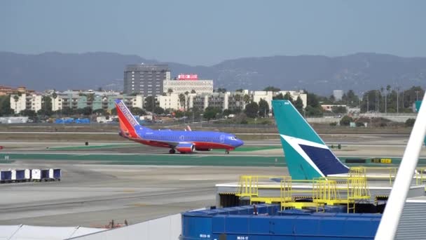 Los Angeles, CA Estados Unidos - 10 02 2019: Aerolíneas del suroeste Boeing 737 aterrizaje en pista de aterrizaje en LAX, Los Angeles International Airport. Los aviones están cerca de las terminales. Tráfico de coches . — Vídeos de Stock