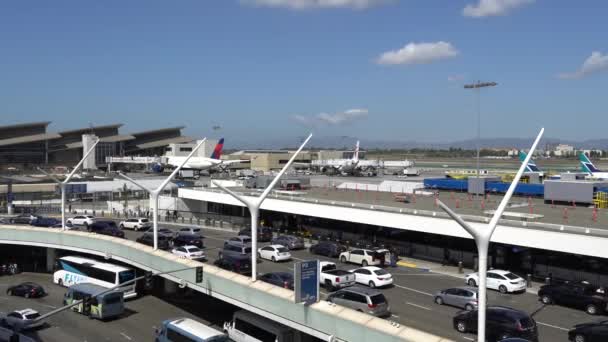 Los Angeles, CA United States - 10 02 2019: Delta airplanes unloading and loading near the terminal at LAX, Los Angeles International Airport. Cars traffic. — ストック動画