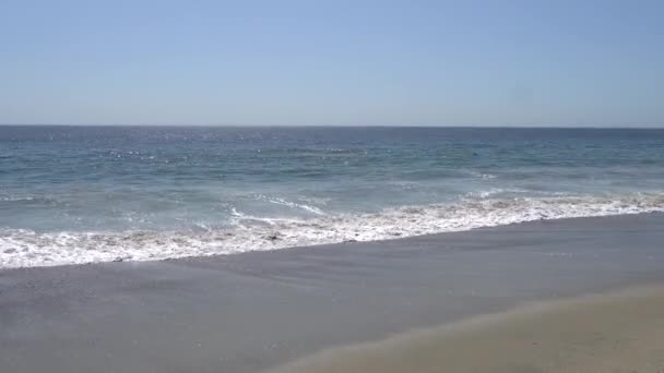 Vlny Pacifického oceánu bily na pobřeží v Malibu Beach Los Angeles California. Teplý slunečný letní den na pláži v Malibu.
