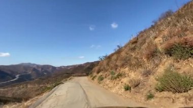 Malibu kanyonunda dar bir yolda araba kullanmak. Yangından sonra görünen ağaçlar ve çalılar yanmış. Malibu California 'da güneşli bir gün..