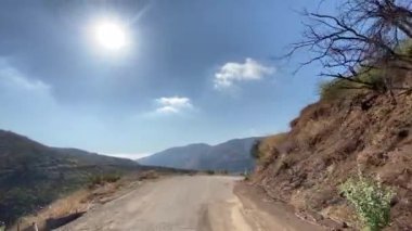 Malibu kanyonunda dar bir yolda araba kullanmak. Yangından sonra görünen ağaçlar ve çalılar yanmış. Malibu California 'da güneşli bir gün..