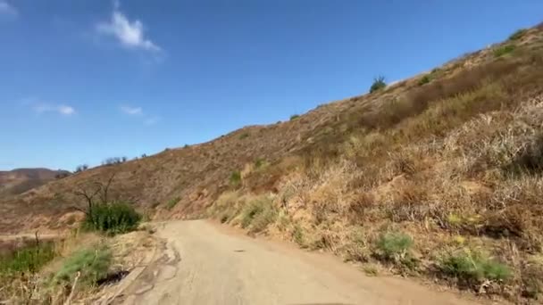 A conduzir um carro numa estrada estreita no desfiladeiro Malibu. Arbustos queimados visíveis e árvores após o fogo. Quente dia ensolarado em Malibu Califórnia EUA . — Vídeo de Stock