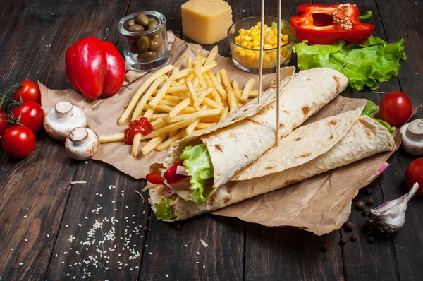 Stock image Sandwiches twisted roll Tortilla two pieces and french fries on a wooden background