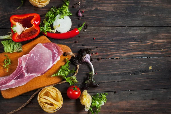 Fondo de la comida italiana, con carne, tomates, espaguetis, ajo, granos de pimienta, chile en la mesa de madera — Foto de Stock