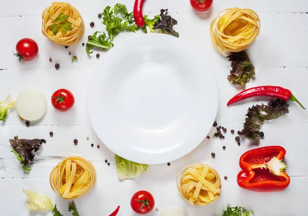Bir beyaz plaka yer metin, çerçeve ahşap rustik arka plan üstten görünüm üzerinde etrafında spagetti, cherry domates, yemek pişirmek için malzemeler biber