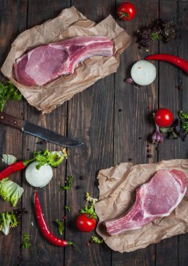 Üstten Görünüm taze çiğ domuz eti boyun biftek kraft kağıt koyu ahşap arka plan üzerinde baharatlar ile.