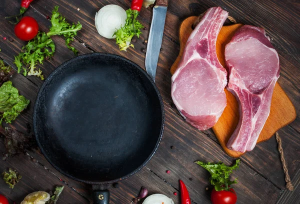 Çiğ domuz biftek otlar, biber ve sarımsak metin, çerçeve ahşap rustik arka plan en iyi görünüm için pan yer çevresinde