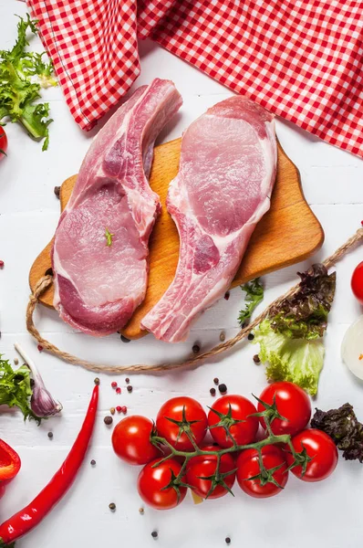 Dos filetes de cerdo con cuchillo de carne y tenedor, condimentos frescos especias sobre fondo de madera rústico oscuro, vista superior —  Fotos de Stock
