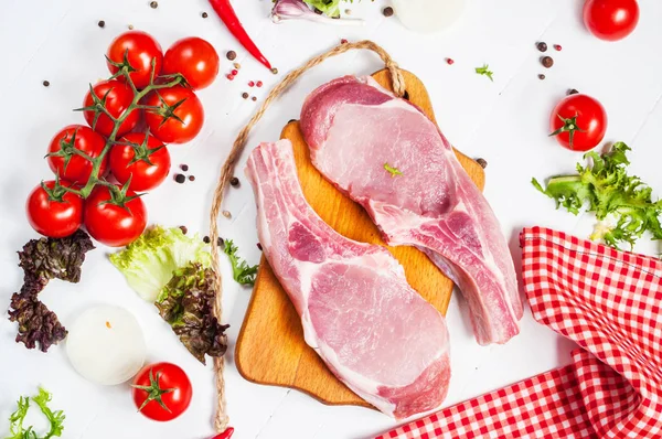 Dos filetes de cerdo con cuchillo de carne y tenedor, condimentos frescos especias sobre fondo de madera rústico oscuro, vista superior — Foto de Stock