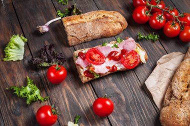 Jambon, domates ve koyu arka plan üzerinde salata ile ciabatta sandviç