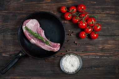 Ham sığır eti biftek ve koyu ahşap bir masa üzerinde kiraz domates.