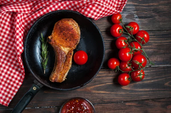 Steak in frying pan and cherry tomatoes on table close up — Stock Photo, Image