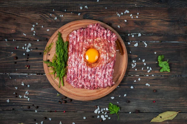 Viande hachée crue maison avec oeuf et herbes gros plan, vue de dessus — Photo