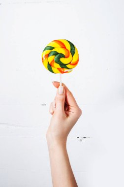 Beyaz ahşap arka plan üzerinde izole lolipop tutan el