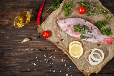 taze tilapia taze biberiye ve limon ile koyu ahşap dokulu arka plan üzerinde. Mutfak Akdeniz deniz ürünleri