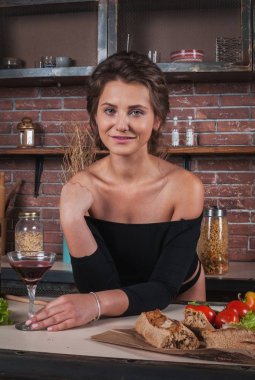 Kırmızı şarap cam tutan mutfakta duran genç kadın