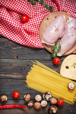 Makarna malzemeler. Domates, spagetti makarna, tavuk fileto ve ahşap masa üzerinde mantar.