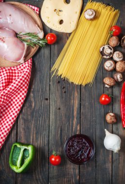 Makarna malzemeler. Domates, spagetti makarna, tavuk fileto ve ahşap masa üzerinde mantar.