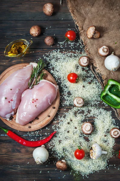 Chiken breast On a cutting board with herbs different fruits and vegetables on rustic wooden background top view — Stock Photo, Image