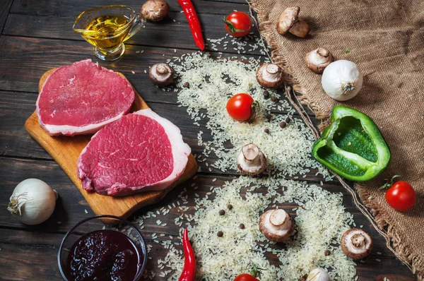 Ingredientes para cocinar una cena de carne saludable. Filetes de ternera crudos sin cocer con champiñones, arroz, hierbas y especias sobre fondo de mesa —  Fotos de Stock