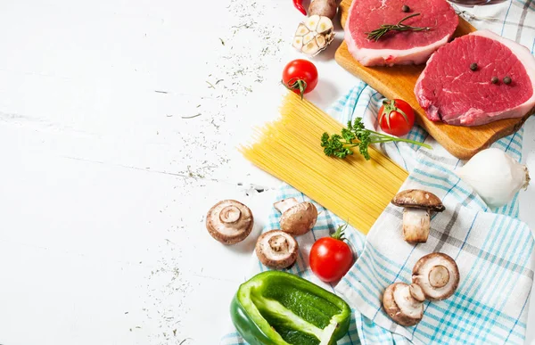 Filete de res crudo con pasta, tomates, champiñones y queso sobre fondo de mesa blanco, espacio para copiar —  Fotos de Stock