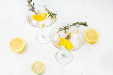 Cin, limon, biberiye fizz, bal ve beyaz zemin üzerine taze otlar ile kokteyl