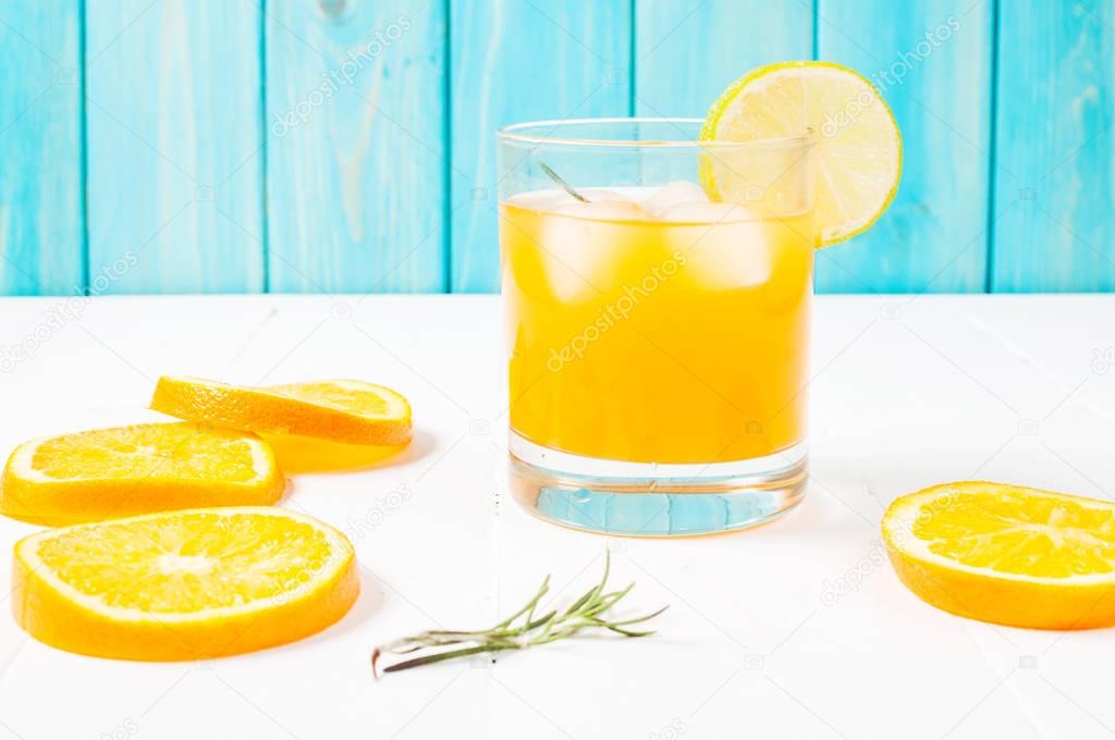 Glass of orange juice on wooden table, on wood plants background, fresh drink.