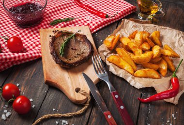 Izgara dana biftek pişmiş patates ve kırmızı sıcak biber taze kiraz domates ile ahşap bir gemide hizmet baharatlar ile terbiyeli