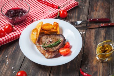 Izgara dana biftek pişmiş patates ve kırmızı sıcak biber taze kiraz domates ile ahşap bir gemide hizmet baharatlar ile terbiyeli