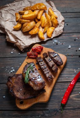 Izgara dana biftek fırında patates ve red hot chili peppers ile ahşap bir gemide servis baharatlar ile terbiyeli