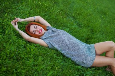 Çimenlerin üzerinde döşeme çok gülümseyen genç kadın portresi yakın yaz zevk onu tatil, doğal olun kırmızı kıllar kadar sevinç.