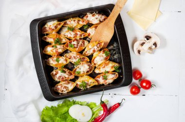 İtalyan makarna peynir ve et Beyaz ahşap masa üzerinde Conchiglioni Rigati dolması.