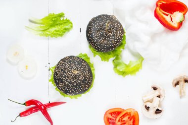 Beyaz ahşap arka plan üzerinde siyah hamburger tavuk göğsü, peynir, domates, salata ile servis