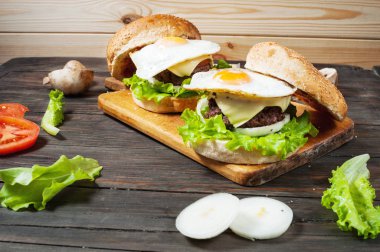 İki ev yapımı sığır eti hamburger ile ahşap masa üzerinde yumurta.