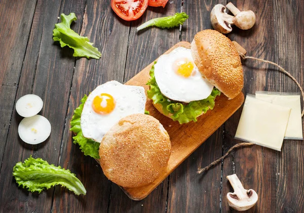 Due hamburger di manzo fatti in casa con uovo sul tavolo di legno . — Foto Stock
