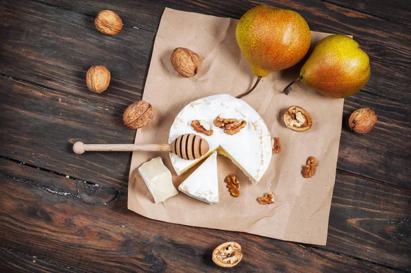 Сир камамбер з волоськими горіхами, медом і грушами на сільському столі — стокове фото