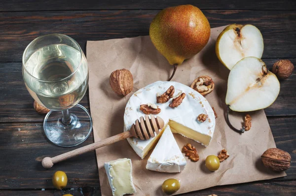 Сир камамбер з волоськими горіхами, медом і грушами на сільському столі . — стокове фото