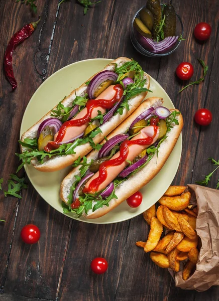 Cachorro quente a bordo com molho e batatas fritas em uma mesa de madeira . — Fotografia de Stock