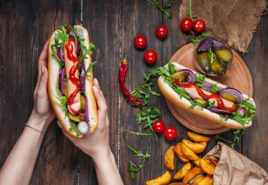 Sosisli sandviç ahşap bir masa üzerinde kadınların elinde. Sayfanın Üstü