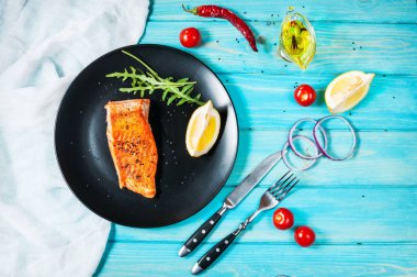 Tek parça limon siyah plaka ile pişmiş somon. Mavi ahşap arka plan