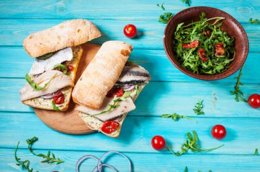 sandviç ringa balığı ve mavi ahşap masa üzerinde Roka Salatası ile