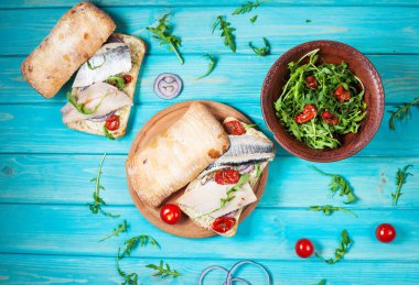 sandviç ringa balığı ve mavi ahşap masa üzerinde Roka Salatası ile