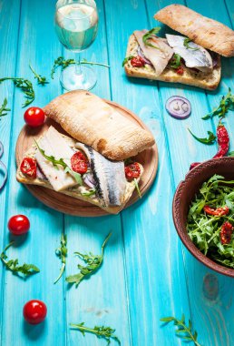 sandviç ringa balığı ve mavi ahşap masa üzerinde Roka Salatası ile