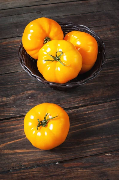 Tomates amarillos en una canasta de mimbre sobre fondo de madera . — Foto de Stock